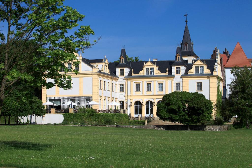 a large yellow house with a large grass field at Schloss und Gut Liebenberg in Liebenberg