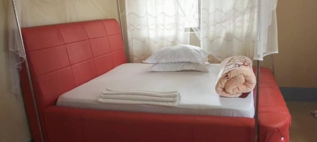 Una cama con marco rojo y toallas. en BM. Beach hotel at Nansio, Ukerewe island, en Hamukoko