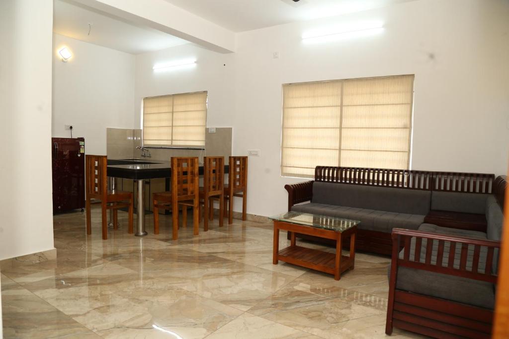 sala de estar con sofá, mesa y sillas en shoreline homestay, en Kozhikode