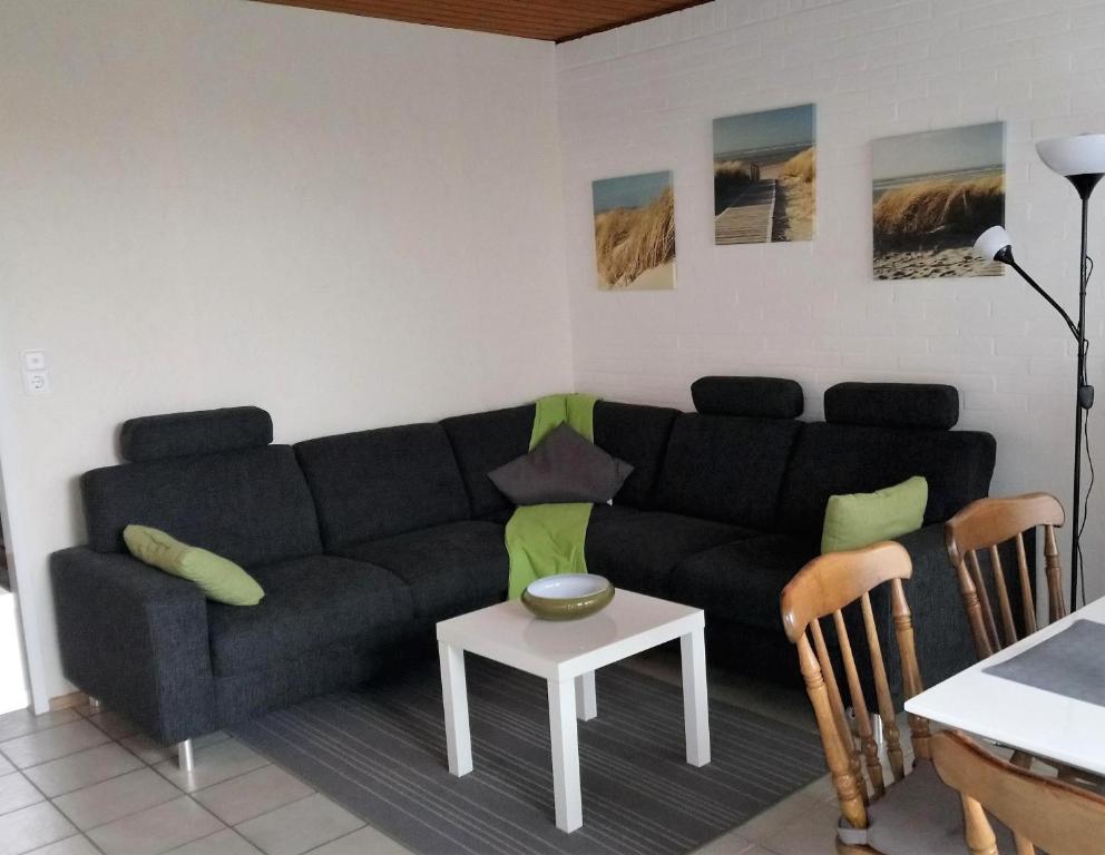 a living room with a black couch and a table at Bungalow 5566 in Tossens in Butjadingen OT Tossens