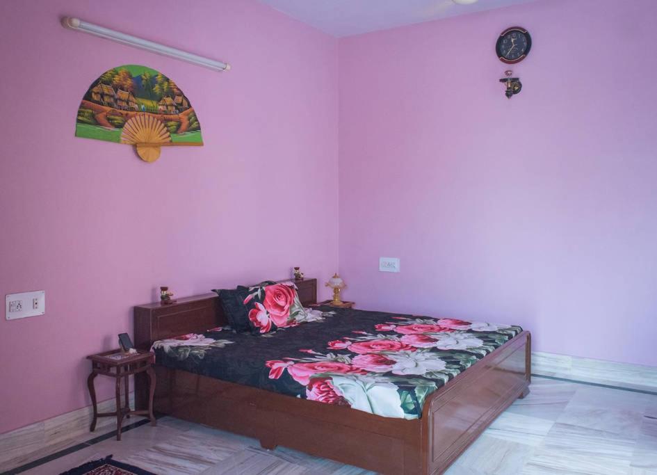 a bedroom with a bed in a room with pink walls at Chopasani Room in Jodhpur