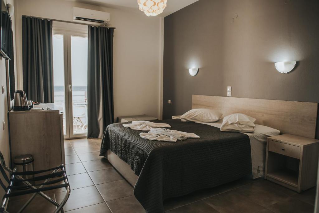 a bedroom with a bed with a black blanket and a window at Bianco Resort in Parga
