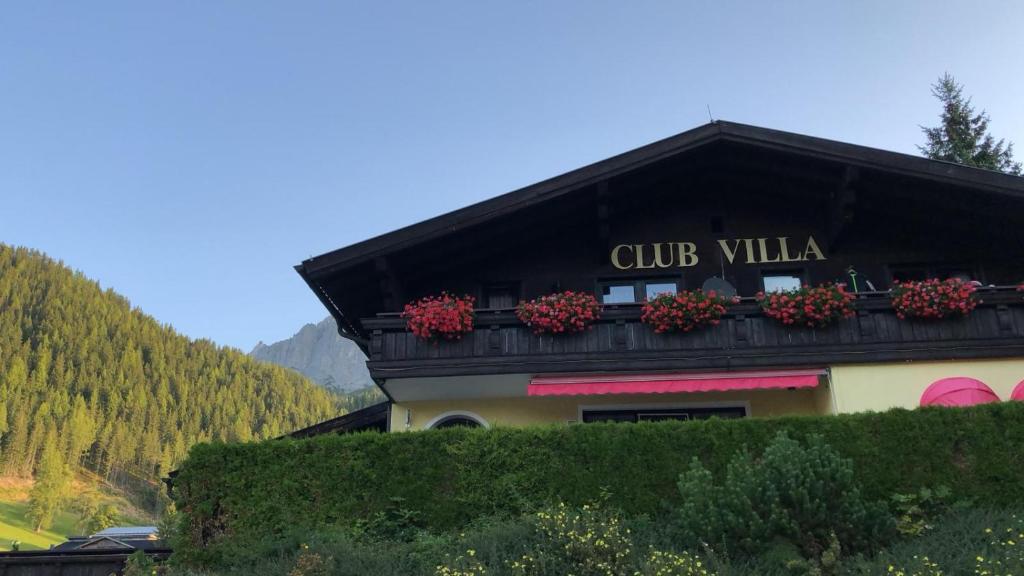 un bâtiment avec des boîtes de fleurs en haut dans l'établissement Club Villa, à Ramsau am Dachstein