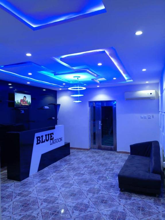 Habitación azul con sofá y TV. en Blue Lagoon Hotel, en Lagos