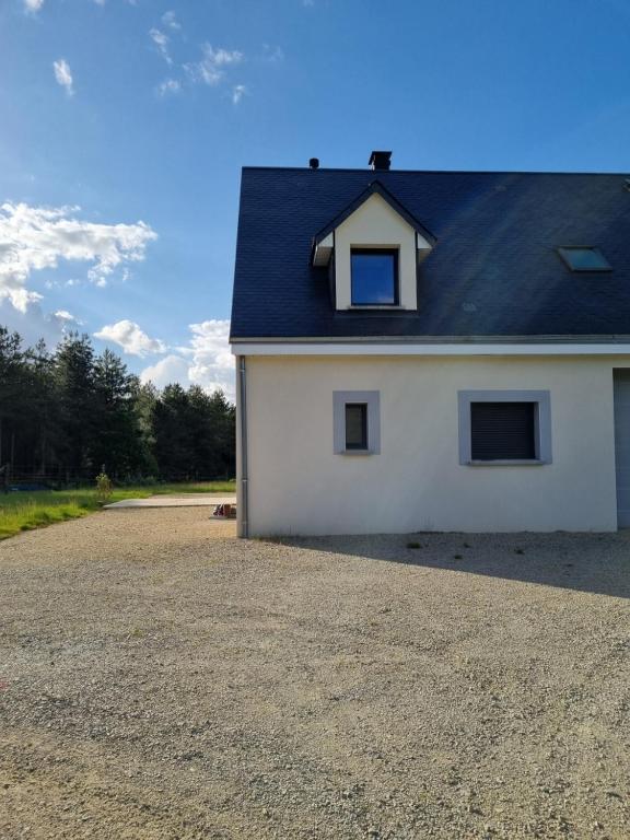 une maison blanche avec un toit noir et une allée en gravier dans l'établissement Maison proche du circuit 24h du Mans, à Fay