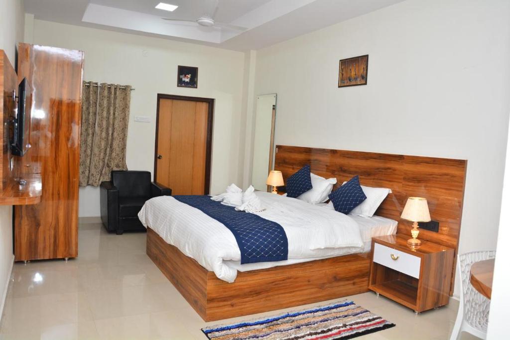 a bedroom with a large bed and a chair at Irctc Hotel in Hospet