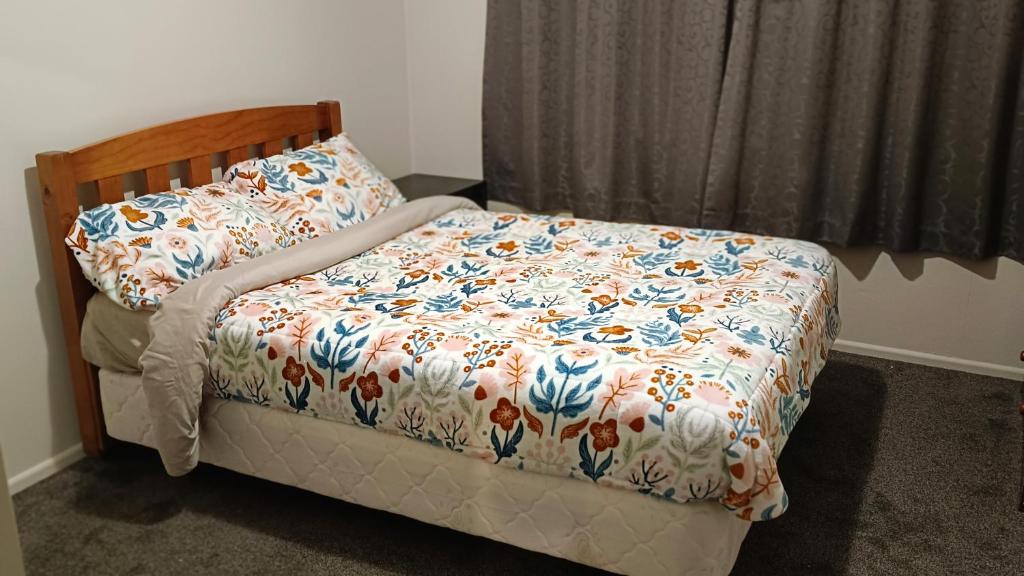 1 dormitorio con 1 cama con edredón de flores en Bowmont, en Invercargill