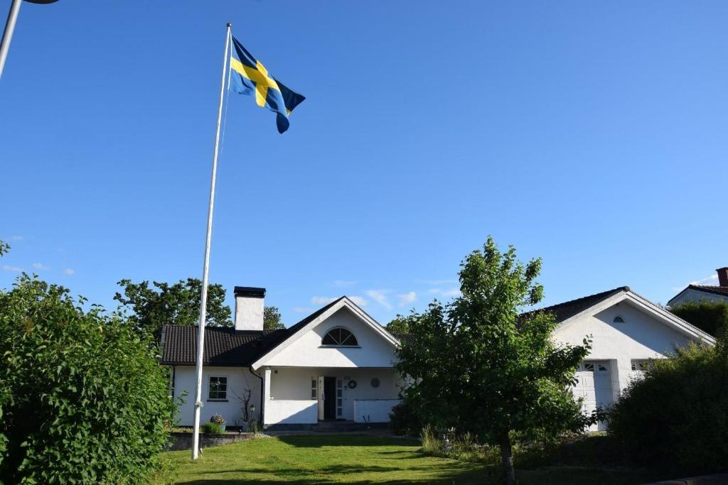 un drapeau devant une maison blanche dans l'établissement Ferienhaus in Håbo mit Privatem Pool, à Skokloster