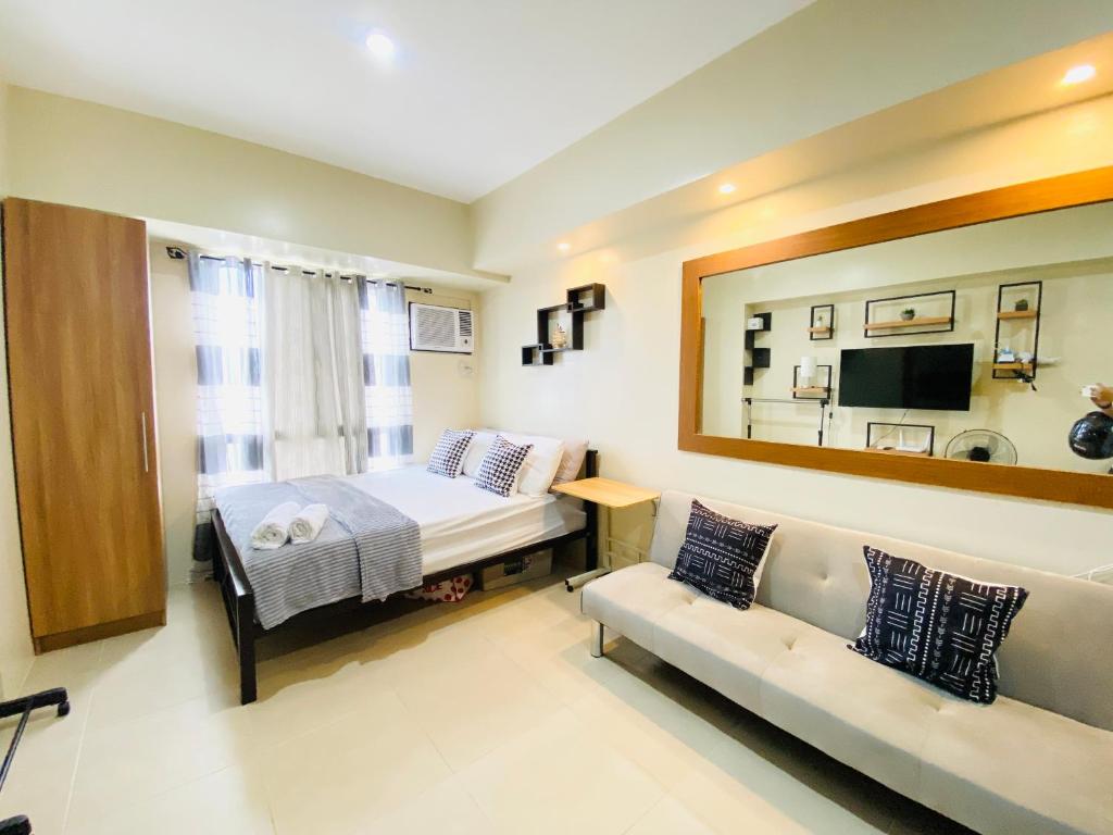a bedroom with a bed and a couch and a mirror at Cebu Avida Riala by P&J in Cebu City