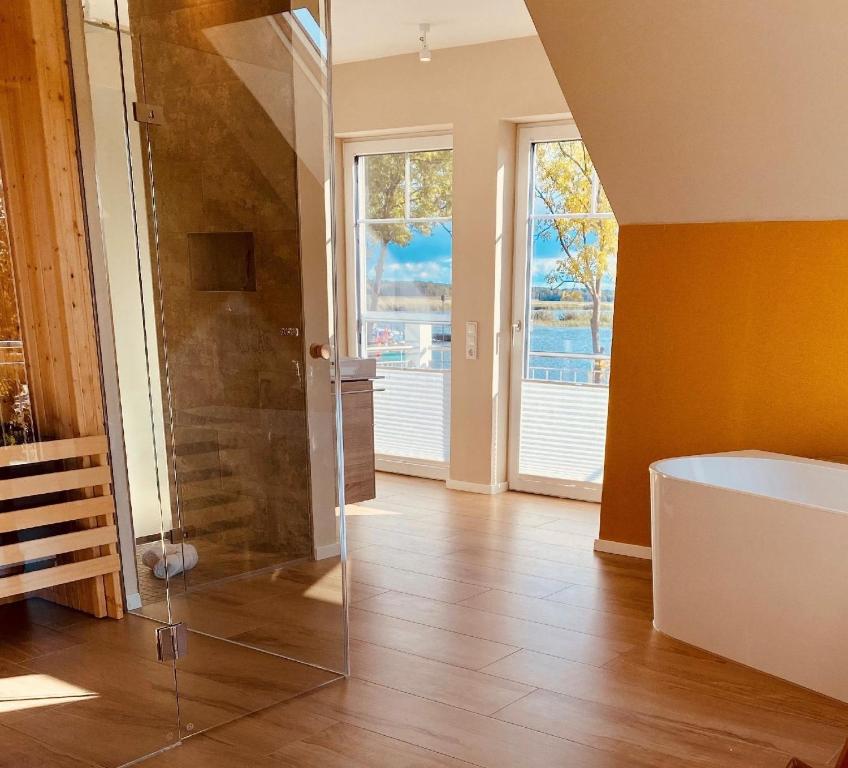 ein Badezimmer mit Badewanne und gläserner Duschkabine in der Unterkunft Ferienhaus Am Hafen 11 Altwarp mit Sauna, Kamin und Wasserblick in Altwarp