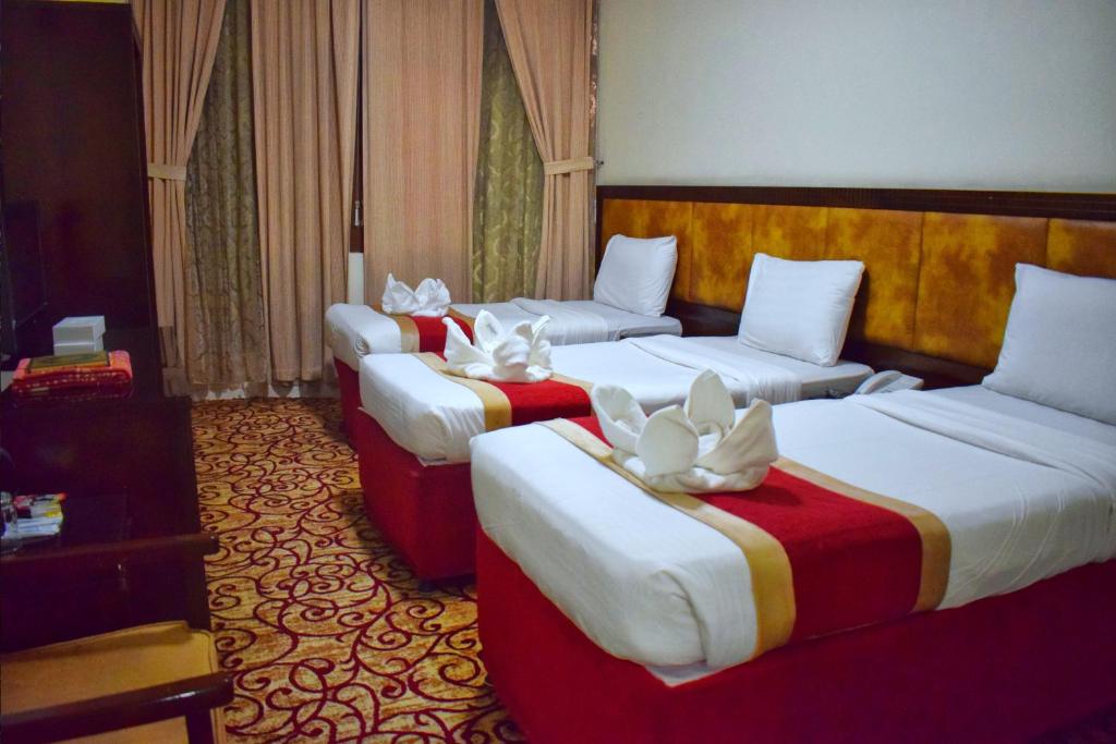 a hotel room with three beds with white flowers on them at وفادة الزهراء in Al Madinah