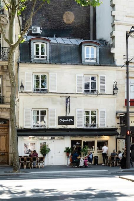 Un bâtiment blanc avec des personnes assises à l'extérieur dans l'établissement PAVILLON EDEN, à Paris