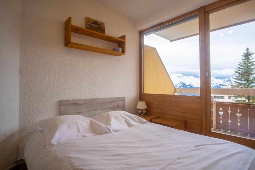 une chambre avec un lit blanc et une grande fenêtre dans l'établissement Studio de la Trafolée - Welkeys, à Huez