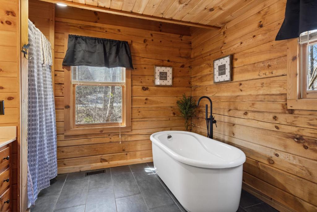 La salle de bains est pourvue d'une baignoire blanche et de murs en bois. dans l'établissement Cozy family friendly Cabin with hot tub, near Gatlinburg, Pigeon Forge, Dollywood, à Sevierville