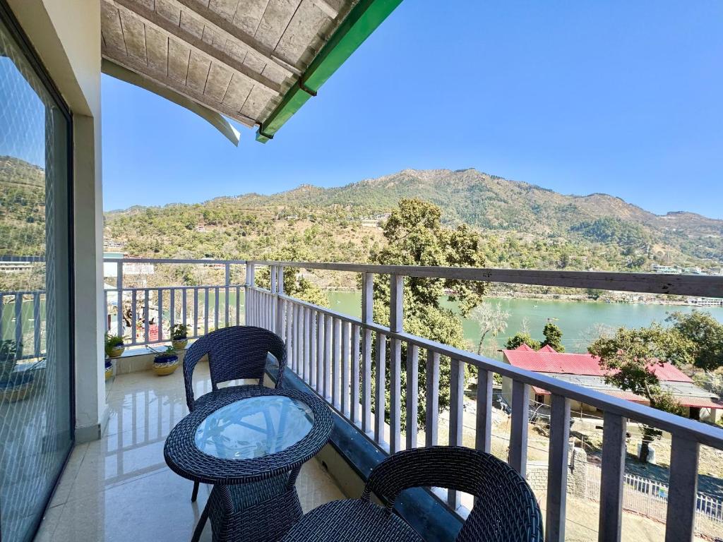 a balcony with two chairs and a view of the water at Wanna Stay Bhimtal in Bhīm Tāl
