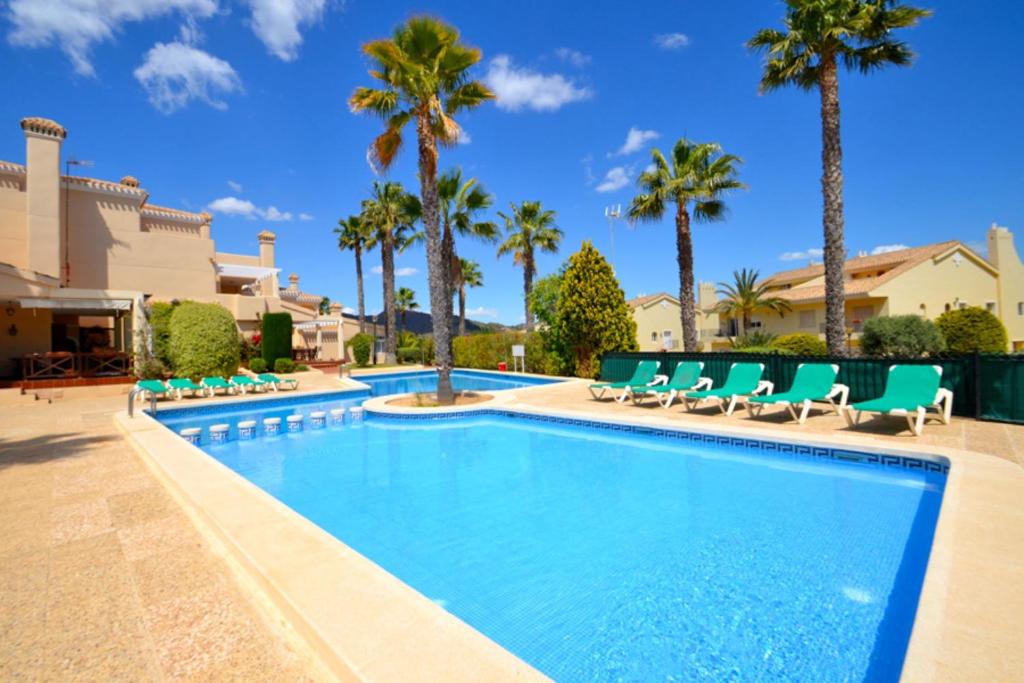a swimming pool with chairs and palm trees at La Manga Club Resort - 3 bedroom Duplex - La Colina in Atamaría