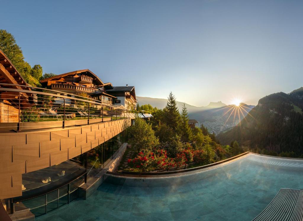 a hotel with a pool and mountains in the background at Charmehotel Uhrerhof - Deur in Ortisei