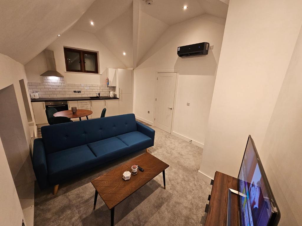 a living room with a blue couch and a tv at Aparotel Serviced Apartments - Stonehenge, Amesbury Town Centre in Amesbury