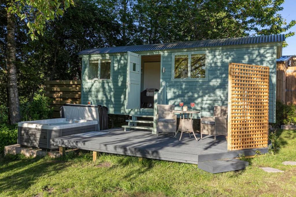 a green tiny house with a table and chairs at Cosy Shepherds Hut with hot tub in the Scottish Highlands in Stittenham