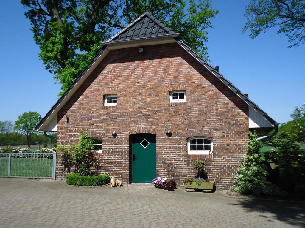 a large brick barn with a green door at Alleinstehendes Ferienhaus in Neusüdende mit Garten in Rastede