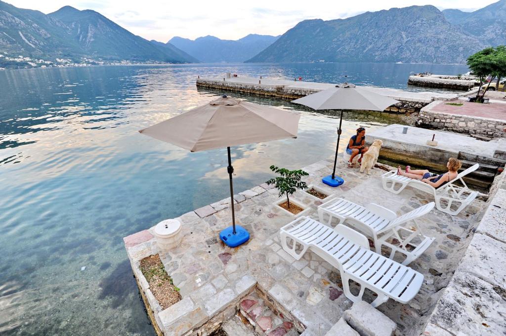 two people sitting in chairs and umbrellas in the water at Apartments Kriva Ulica in Kotor