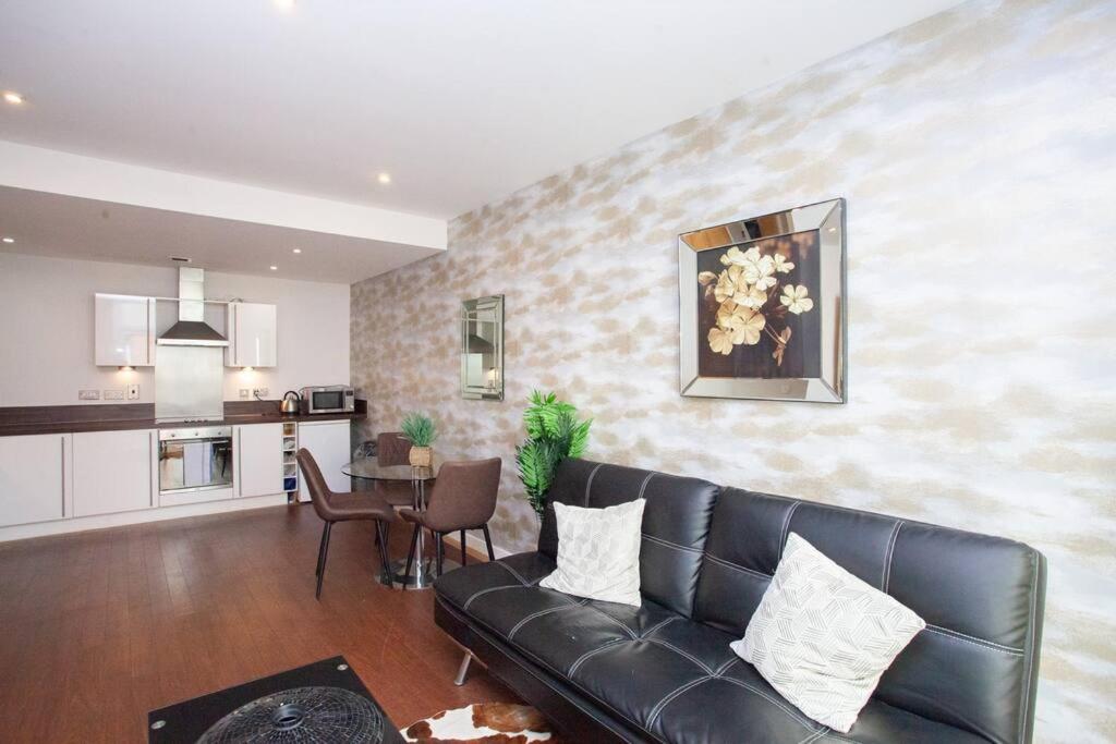 a living room with a black couch and a kitchen at Fantastic City Centre Flat in Glasgow