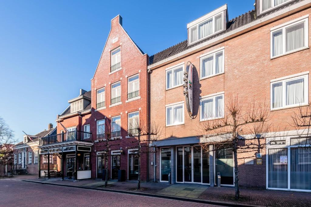 a brick building with a clock on it on a street at Hotel Aalsmeer in Aalsmeer