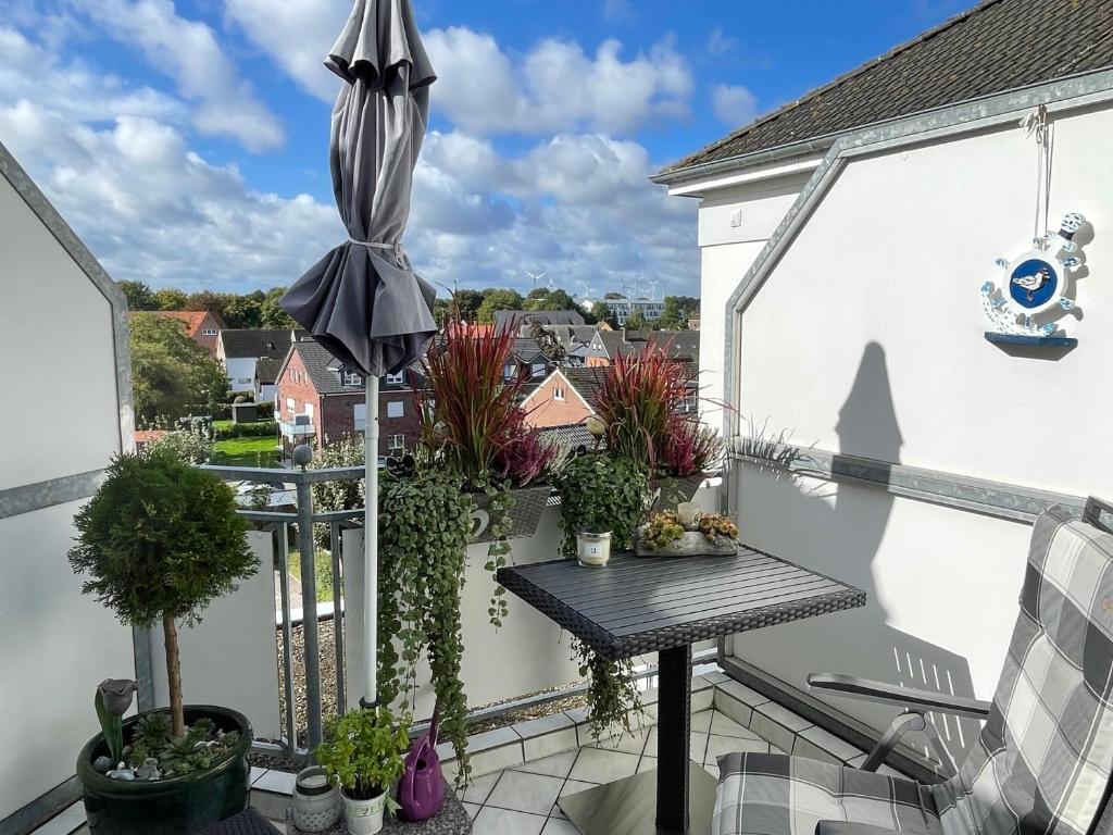 uma varanda com um guarda-chuva e vasos de plantas em "Haus Atlantic" - Wohnung "StrandGut" em Grömitz