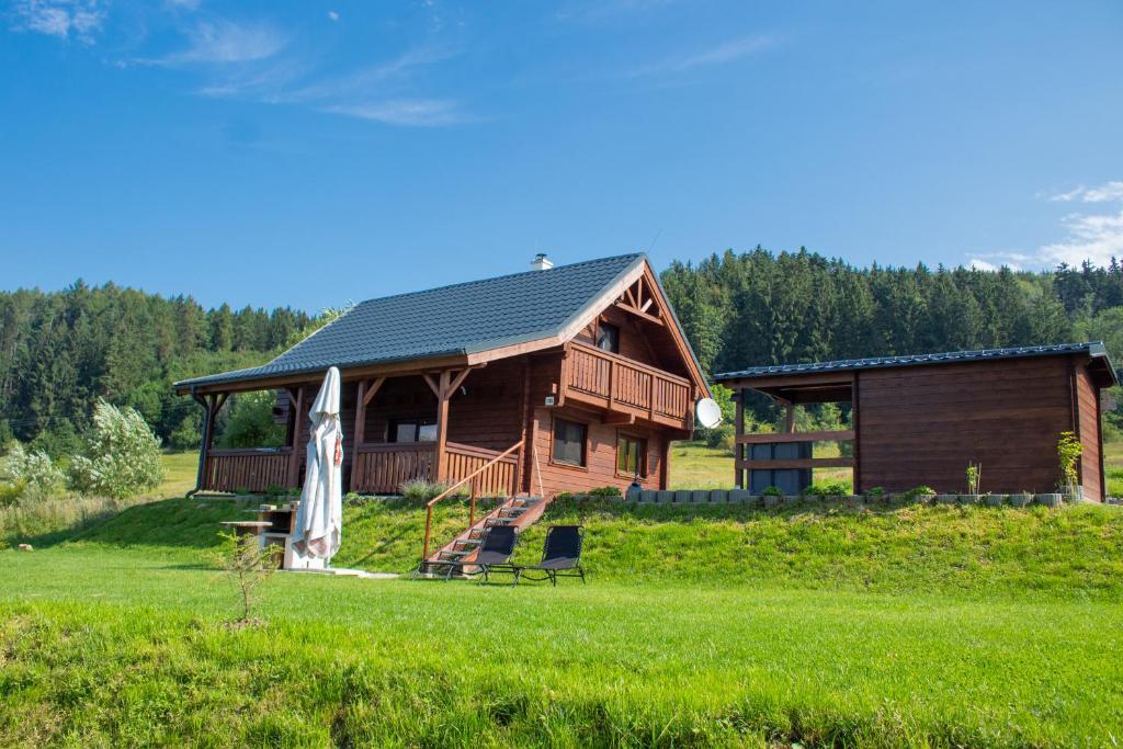 eine Blockhütte mit einer Terrasse und einem Stuhl davor in der Unterkunft Chata Michaela Ľubietová in ľubietová