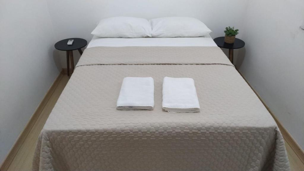 Una cama con sábanas blancas y toallas. en AP Confortável San Inácio, en Santo Ângelo