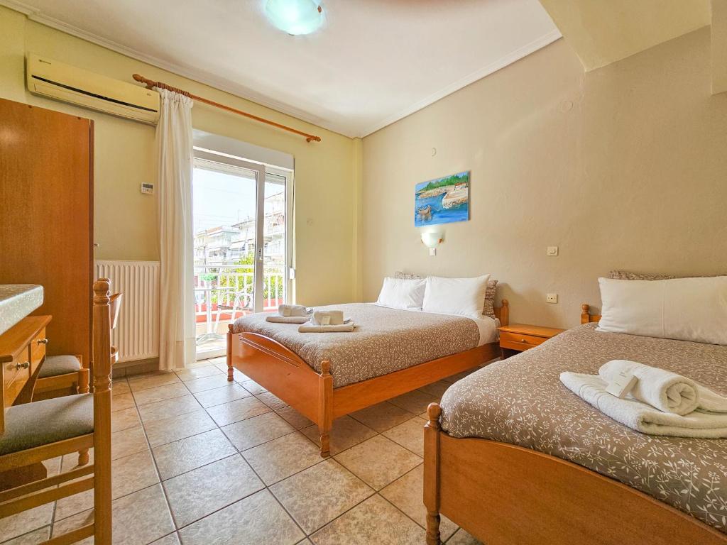a hotel room with two beds and a window at Lucia Hotel Paralia in Paralia Katerinis
