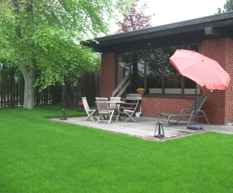 eine Terrasse mit einem Tisch und einem roten Regenschirm in der Unterkunft Ferienhaus für 4 Personen ca 63 m in Möhnesee, Sauerland Möhnesee in Möhnesee