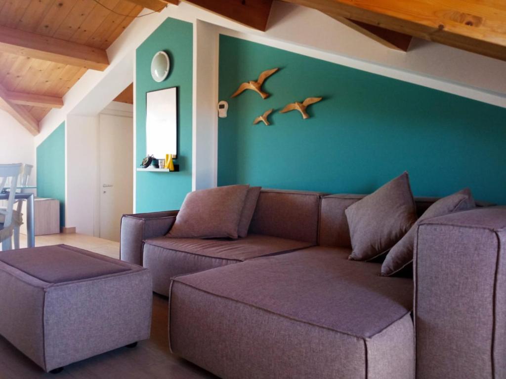 un soggiorno con divano e 2 uccelli sul muro di Mansarda bijoux! 50mt dal mare con ampio terrazzino a Porto Recanati