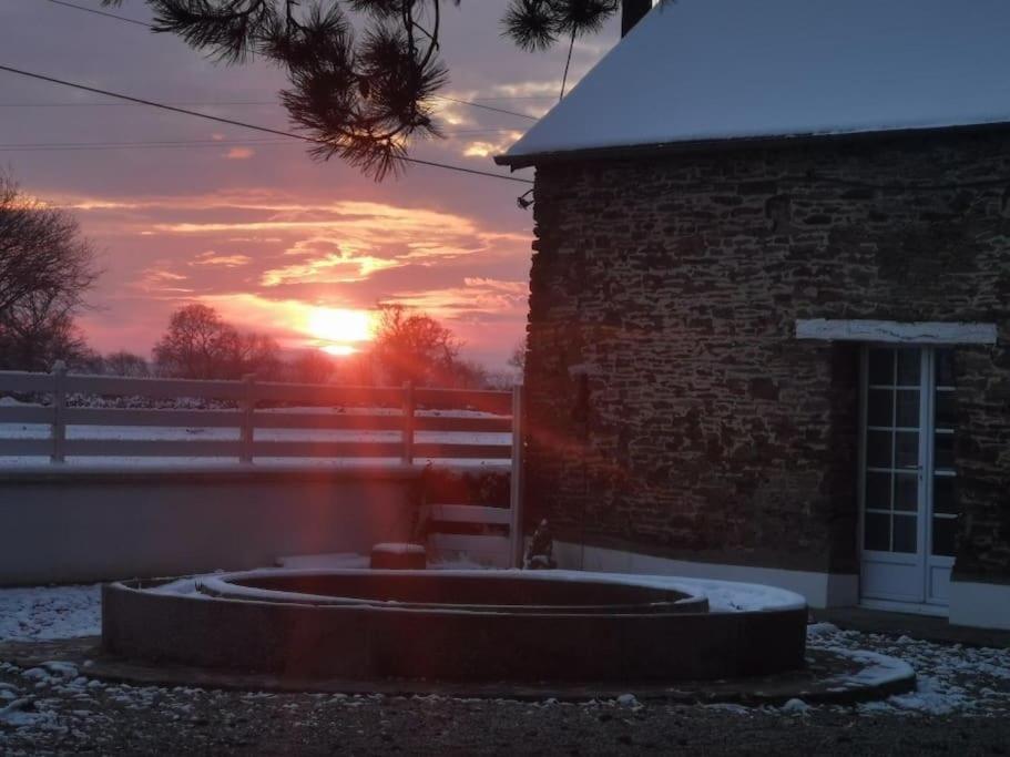 - un coucher de soleil derrière un bâtiment en brique dans l'établissement Les Bruyères cottage, à La Bazoque