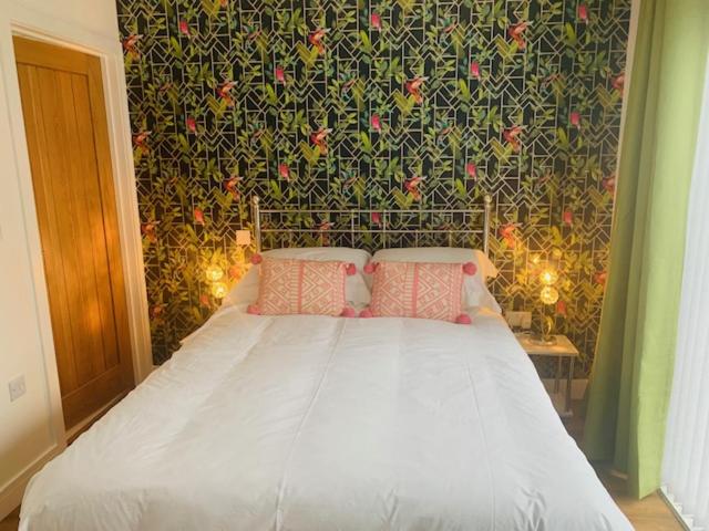 a bedroom with a white bed with a floral wall at Lowen Chy 1 Green Hill in Wadebridge