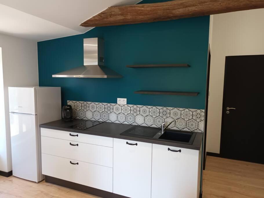 a kitchen with white cabinets and a blue wall at Charmant logement atypique et calme in Mouchamps