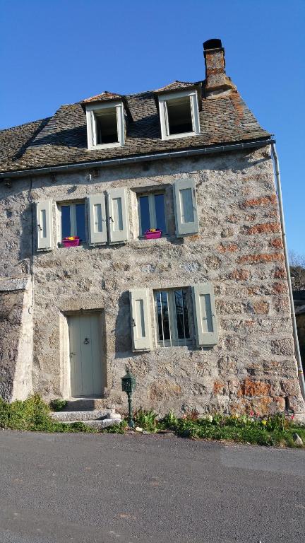 a stone building with three windows and a door at L'AUBRIETE in Recoules-dʼAubrac