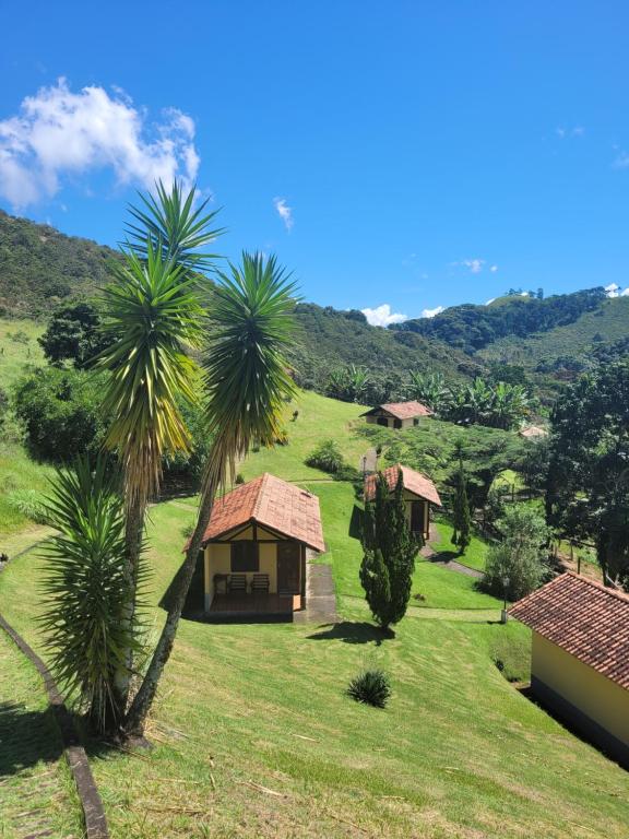 una pequeña casa en una colina con césped y palmeras en Pousada Mirante Santo Antônio, en Rio Prêto