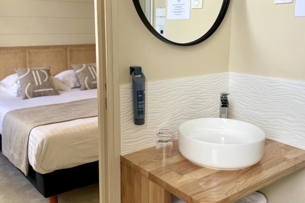 a bathroom with a sink and a bed at Hôtel Les Costans, The Originals Relais in Perros-Guirec