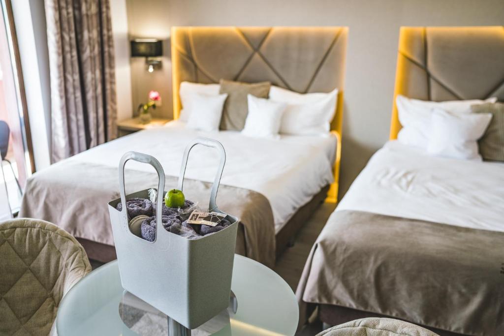 una habitación de hotel con 2 camas y una mesa con una bolsa en Hotel Eden Garden Spa, en Câmpulung Moldovenesc