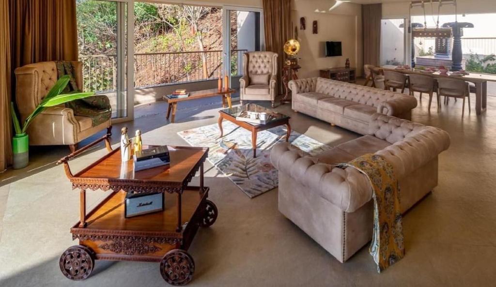 uma grande sala de estar com sofás e mesas em The Woods Worth Villa em Vani