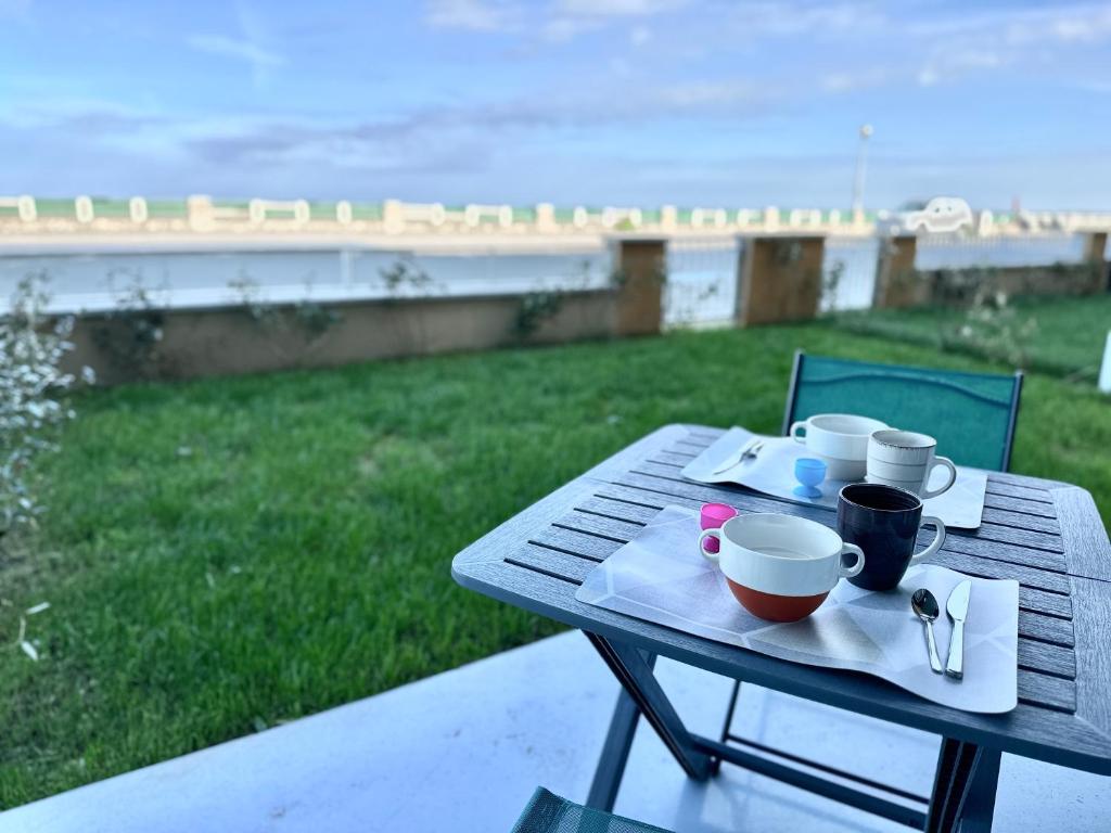 - une table de pique-nique avec des tasses et des soucoupes dans l'établissement Baie Dream appartement en front de mer, à Cayeux-sur-Mer