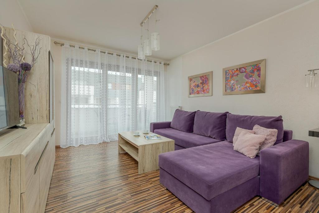 a living room with a purple couch and a table at Spacious Apartment with Balcony in Świnoujście Center by Renters in Świnoujście