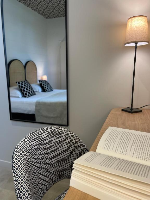 a room with a table with a book and a mirror at Hôtel Les Costans, The Originals Relais in Perros-Guirec