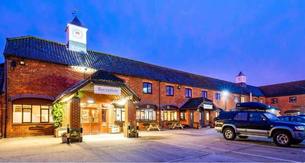 a truck parked in front of a brick building with a clock tower at The Barn Hotel & Spa, Sure Hotel Collection by Best Western in Grantham