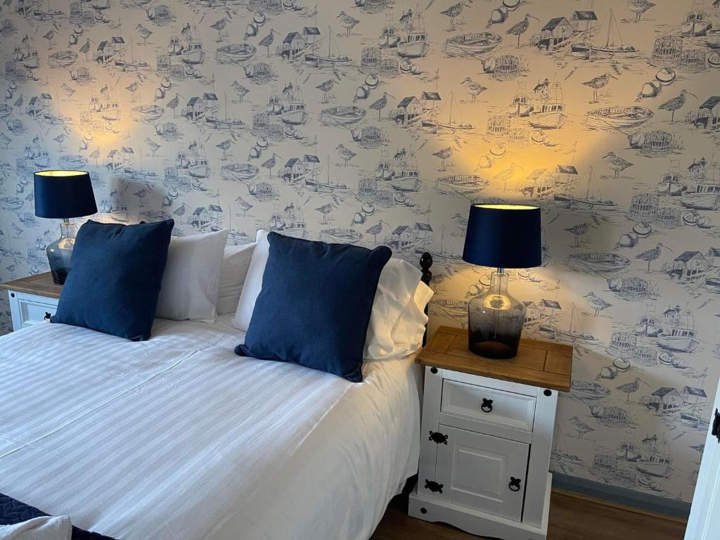 een slaapkamer met een bed met blauwe kussens en 2 lampen bij Durham City Cottages in Durham