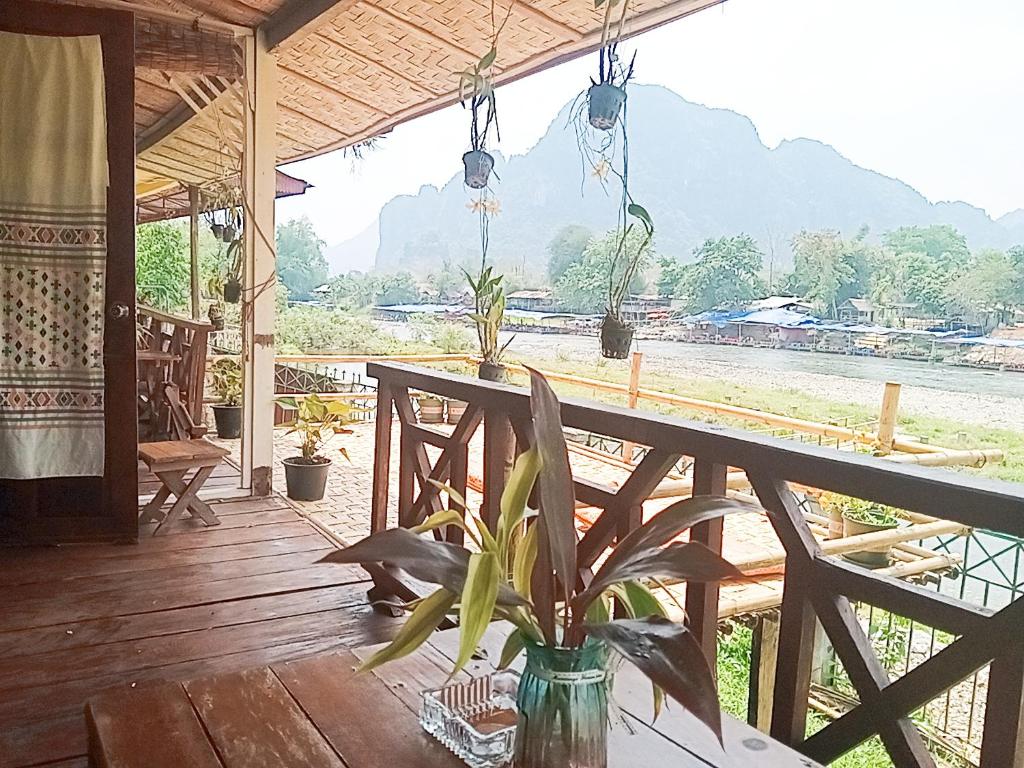 a porch with a table and a view of a river at VangVieng Ruby'Homestay in Vang Vieng