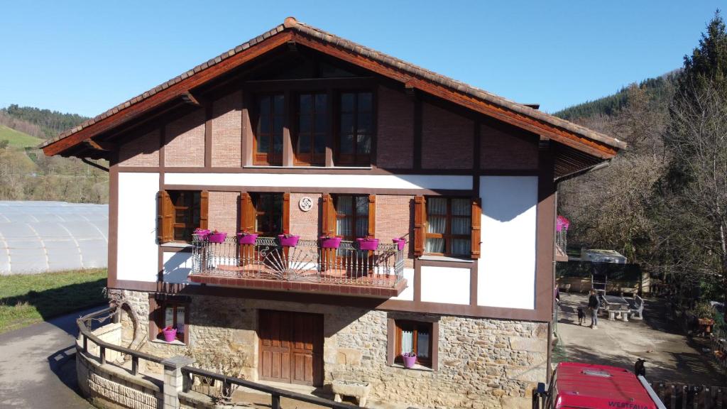 a house with a balcony with purple flowers on it at Caserío Zubieta in Orózqueta