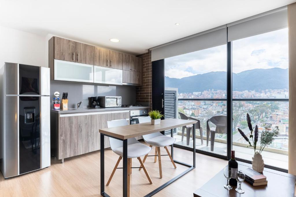 a kitchen with a table and chairs and a large window at 72 HUB Apartments - Great View - Gym - Rooftop in Bogotá