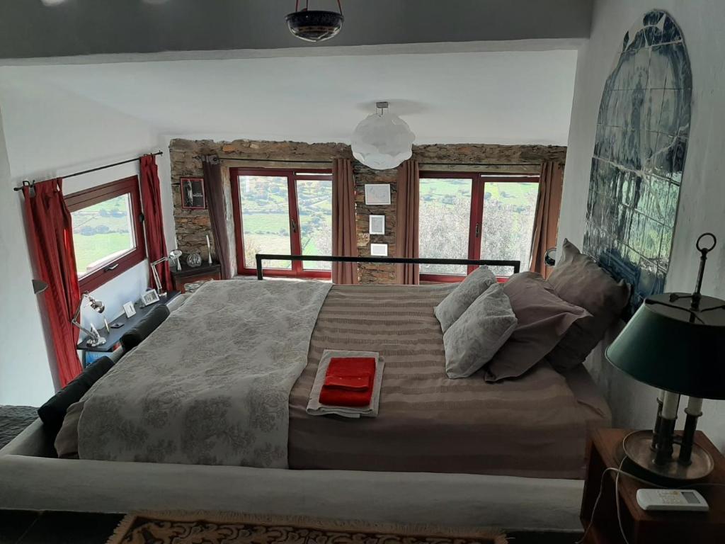 um quarto com uma cama grande e 2 janelas em Casas Letizia e Sebastião em Monsaraz